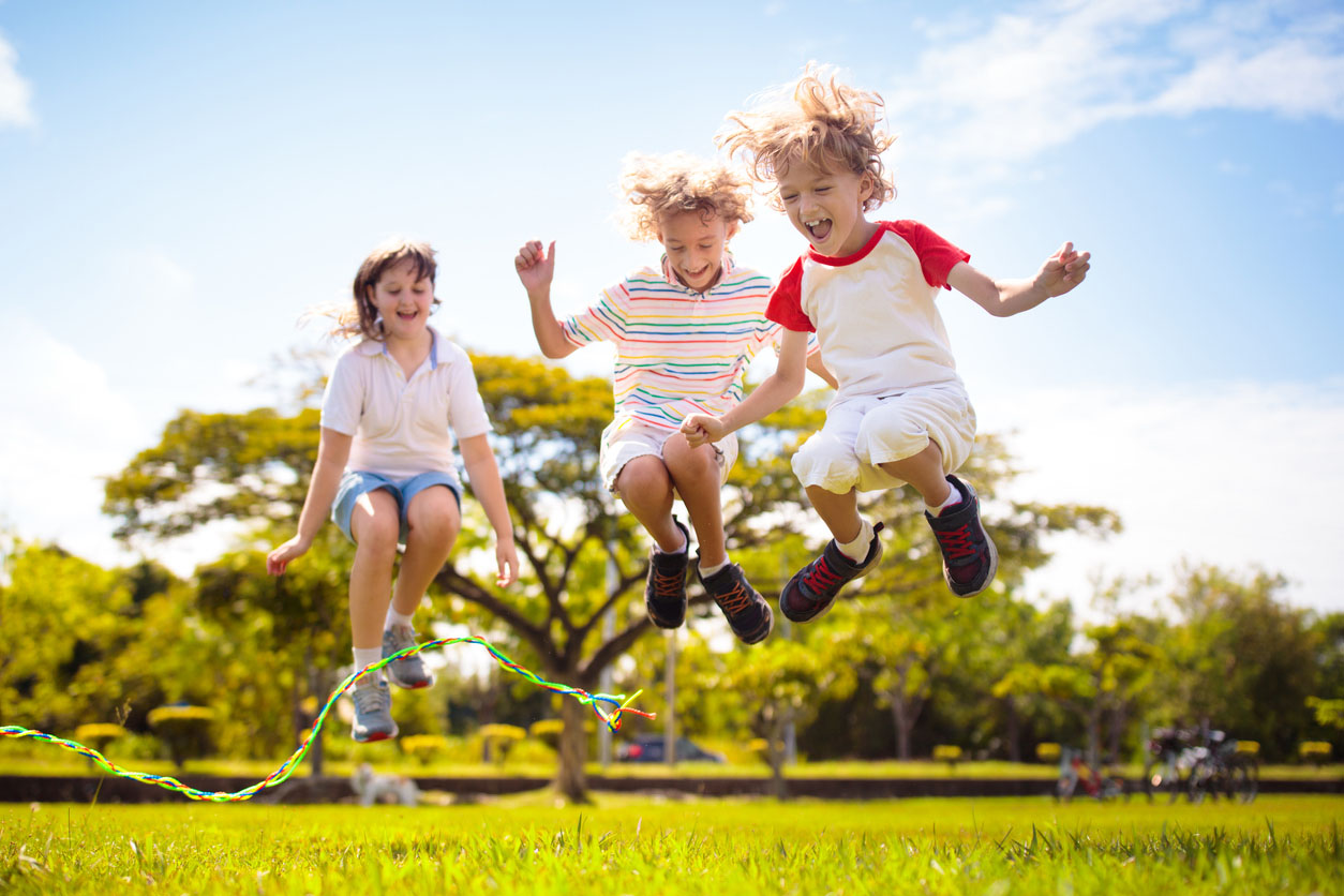Happy kids play outdoor. Children skipping rope.